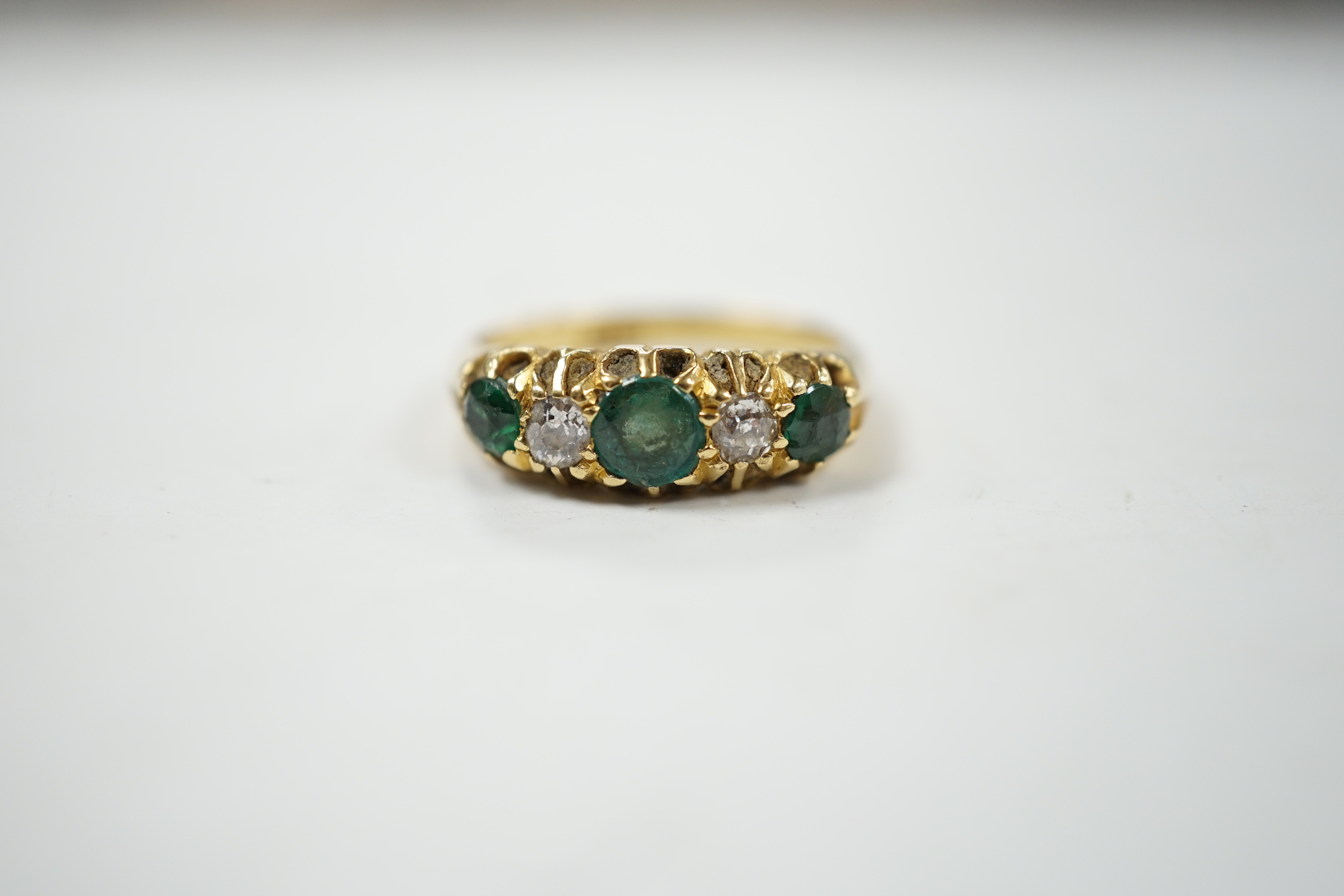 An early 20th century 18ct, three stone green garnet and two stone diamond claw set half hoop ring, size L, gross weight 4.8 grams.